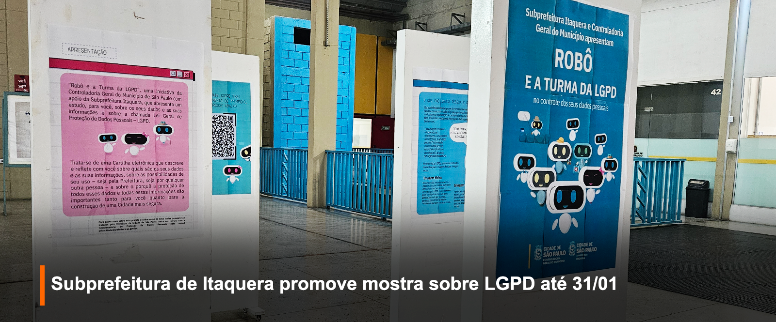 Foto da exposição no salão da Subprefeitura de Itaquera, na imagem tem 4 paineis brancos, cada um com uma página da revista Robê e a Turma da LGPD